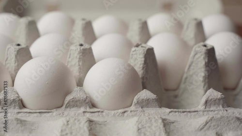 Hand laying out chicken eggs in a cardboard tray, side view
