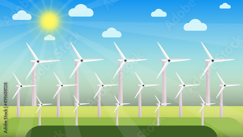 Windmills in different sizes and shapes on a green field. Producing electricity from windmills using the air concept. Windmills in a greenfield on a sunny day. Blue sky with shiny sun and clouds.