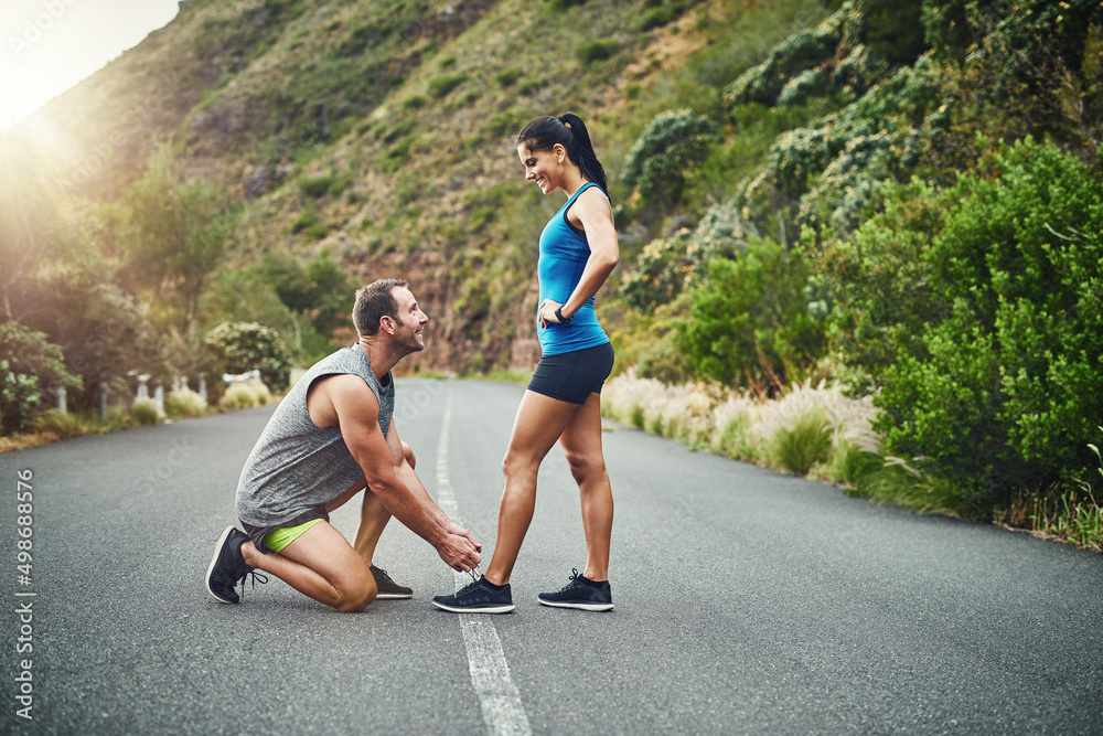He always make sure everything I do is secure. Shot of a young attractive couple training for a marathon outdoors.
