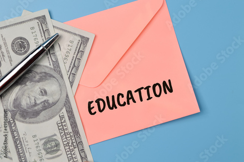 Money banknotes, pen and peach envelope with text EDUCATION