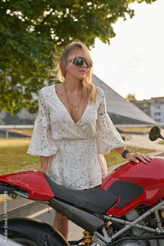 Stylish woman biker with sunglasses and motorcycle outdoors