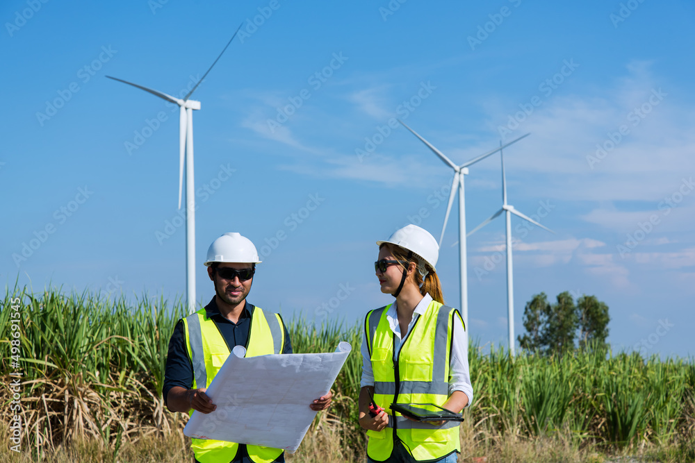 wind turbine and person. Two young maintenance engineer planning discuss Project in wind turbine farm. wind turbine and person. Two young maintenance engineer planning discuss Project in wind turbine farm.