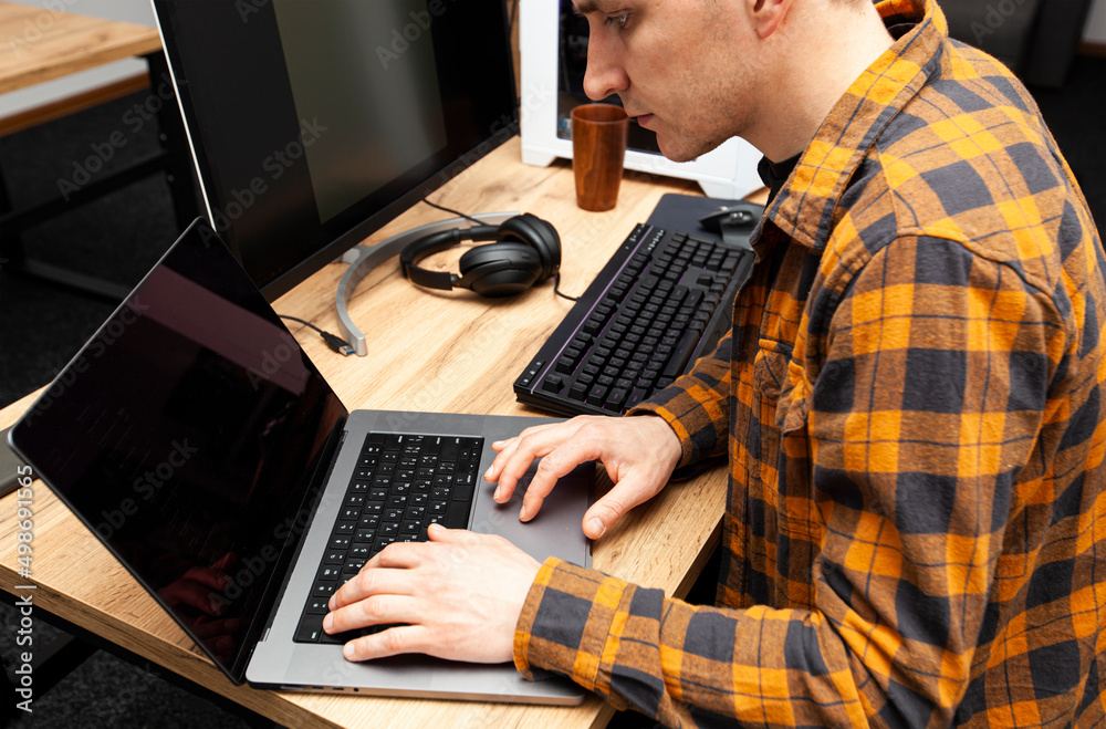 The guy in office working with the laptop and pc in the same time The guy in office working with the laptop and pc in the same time