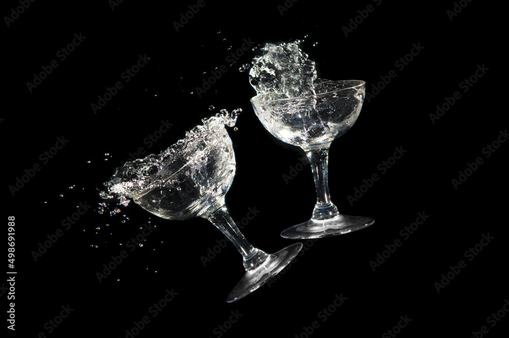 Clinking champagne glass with liquid pouring out on black