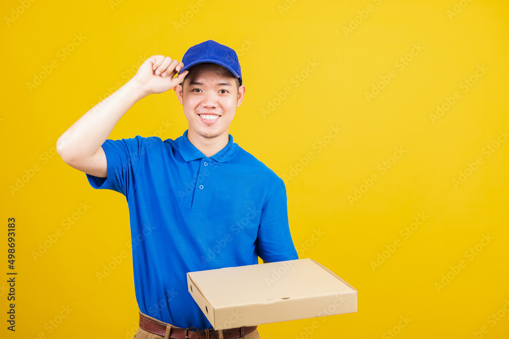 Portrait excited delivery service man standing he smile wearing blue t-shirt and cap uniform hold give food order pizza cardboard boxes looking to camera, studio shot isolated on yellow background Portrait excited delivery service man standing he smile wearing blue t-shirt and cap uniform hold give food order pizza cardboard boxes looking to camera, studio shot isolated on yellow background
