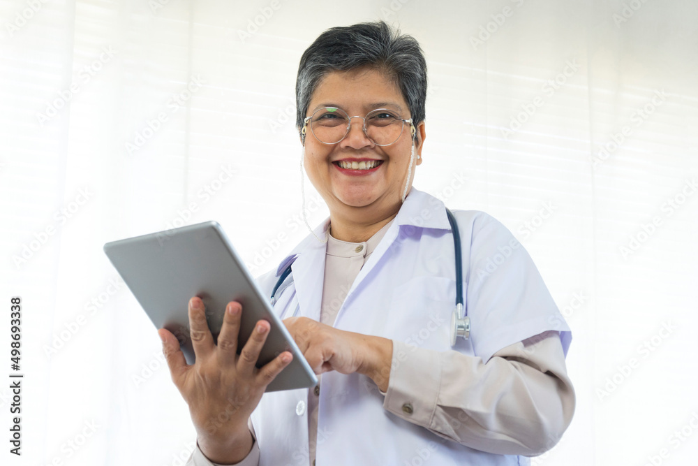 Confident senior female doctor happy using tablet computer standing in clinic. Confident senior female doctor happy using tablet computer standing in clinic.