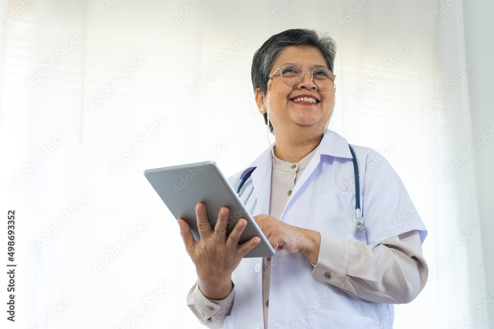 Confident senior female doctor happy using tablet computer standing in clinic. Confident senior female doctor happy using tablet computer standing in clinic.