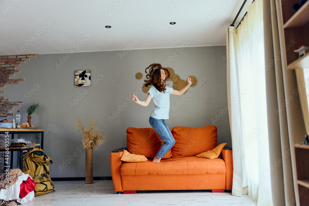 Naklejka premium pretty woman in jeans is standing on the couch fun