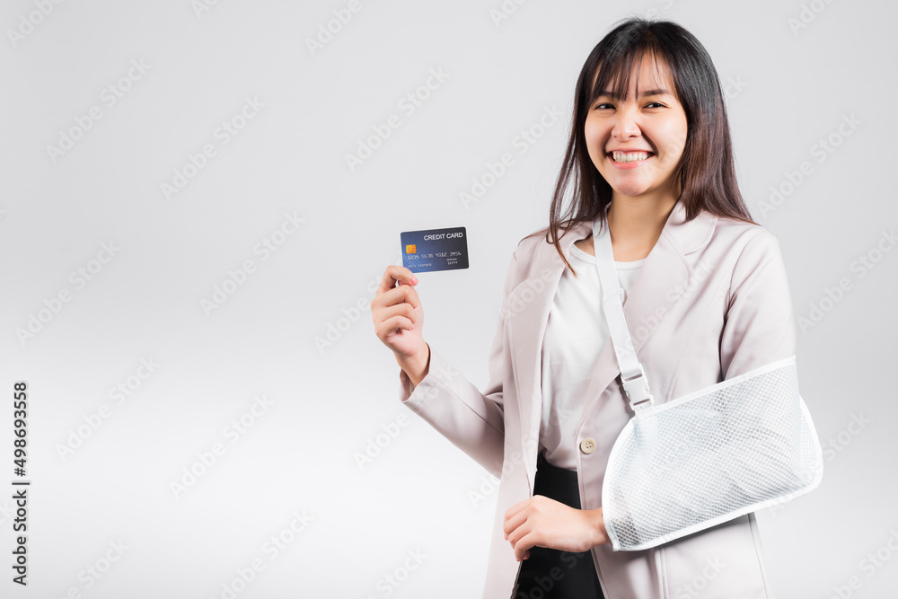 Woman confident smile broken arm after accident and wear arm splint for treatment she emergency pay medical bills by credit card, Happy Asian female sling support hand isolated on white background Woman confident smile broken arm after accident and wear arm splint for treatment she emergency pay medical bills by credit card, Happy Asian female sling support hand isolated on white background