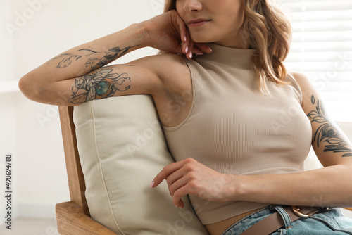 Beautiful woman with tattoos on arms resting at home, closeup