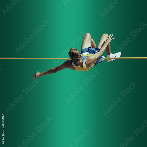 Professional male pole vaulter on background in neon light. Concept of sport, healthy lifestyle, action, movement, motion.