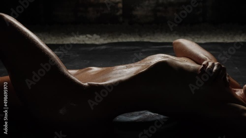 Beautiful tanned body close-up on a black background. Milk is poured on the girl's body close-up