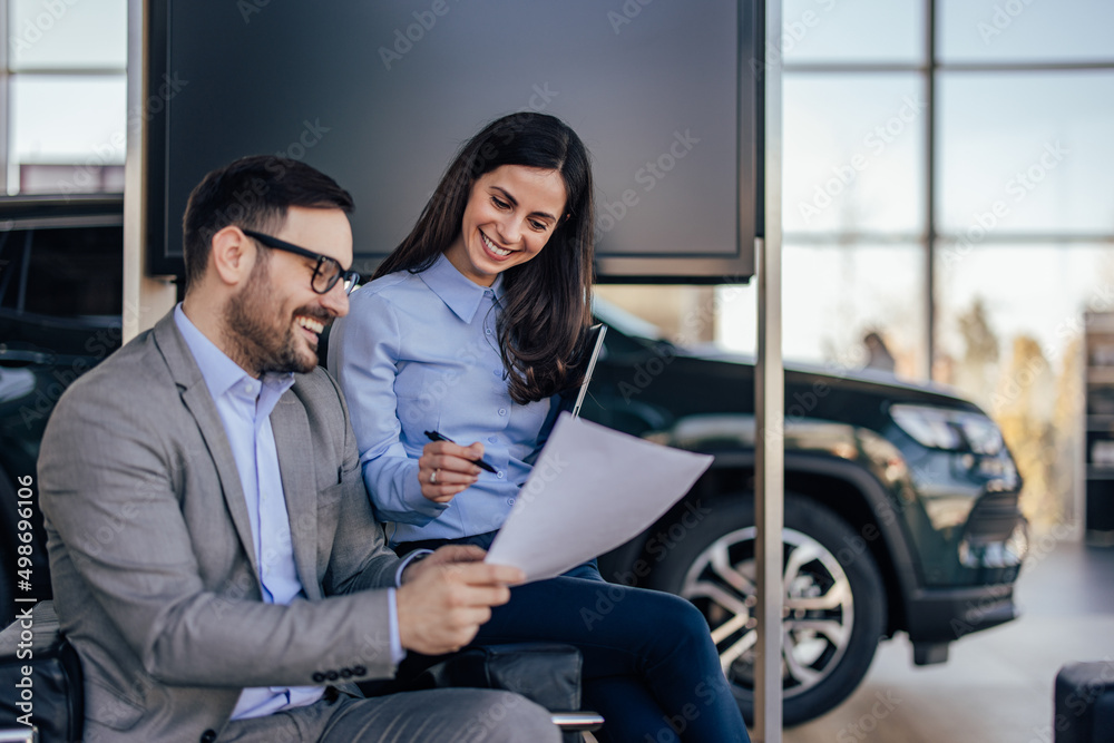 Car in the background, people checking a document together. Car in the background, people checking a document together.