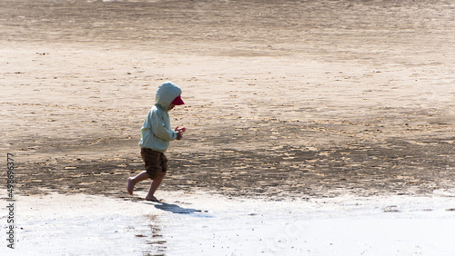 遠浅の海の浜辺で遊ぶ小さな子ども