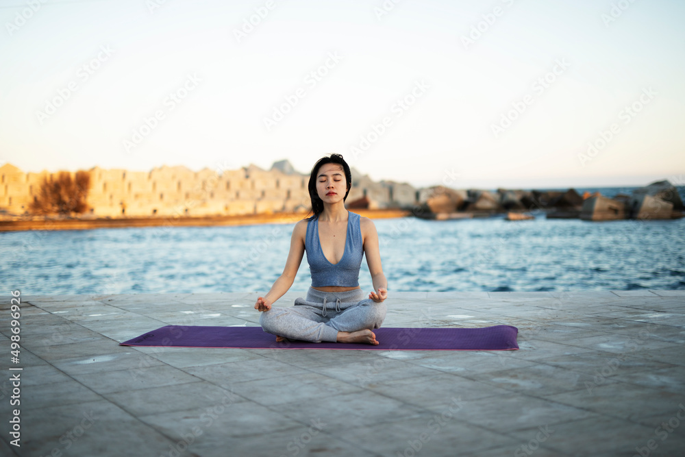 Beautiful young woman stretching outside. Fit woman doing yoga exercise.