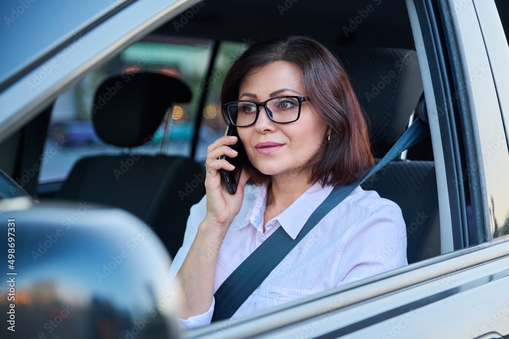 Confident female driver with smartphone driving a car