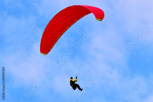 Paragleiter mit rotem Schirm im Flug