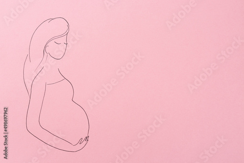 Pregnant woman figure drawn on pink background, top view with space for text. Surrogacy concept