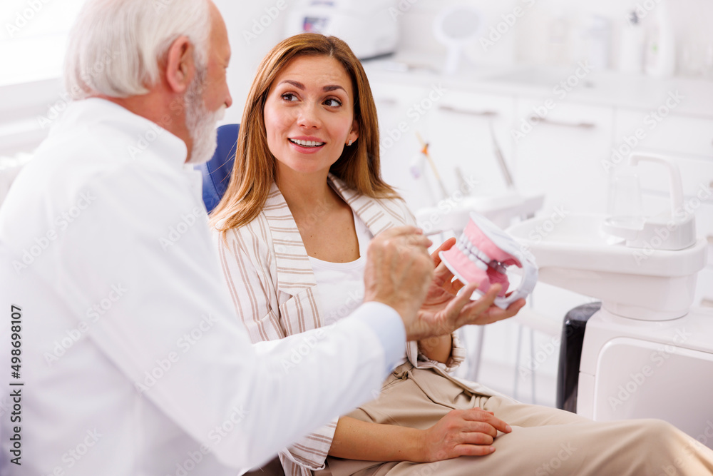 Dentist explaining procedure to patient on plastic jaw model Dentist explaining procedure to patient on plastic jaw model