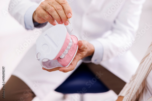 Doctor explaining procedure to patient on plastic jaw model at dentist office