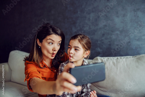 Mother and daughter taking selfie and making silly faces. 