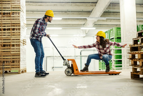 Workers playing with forklift and having fun at workplace.