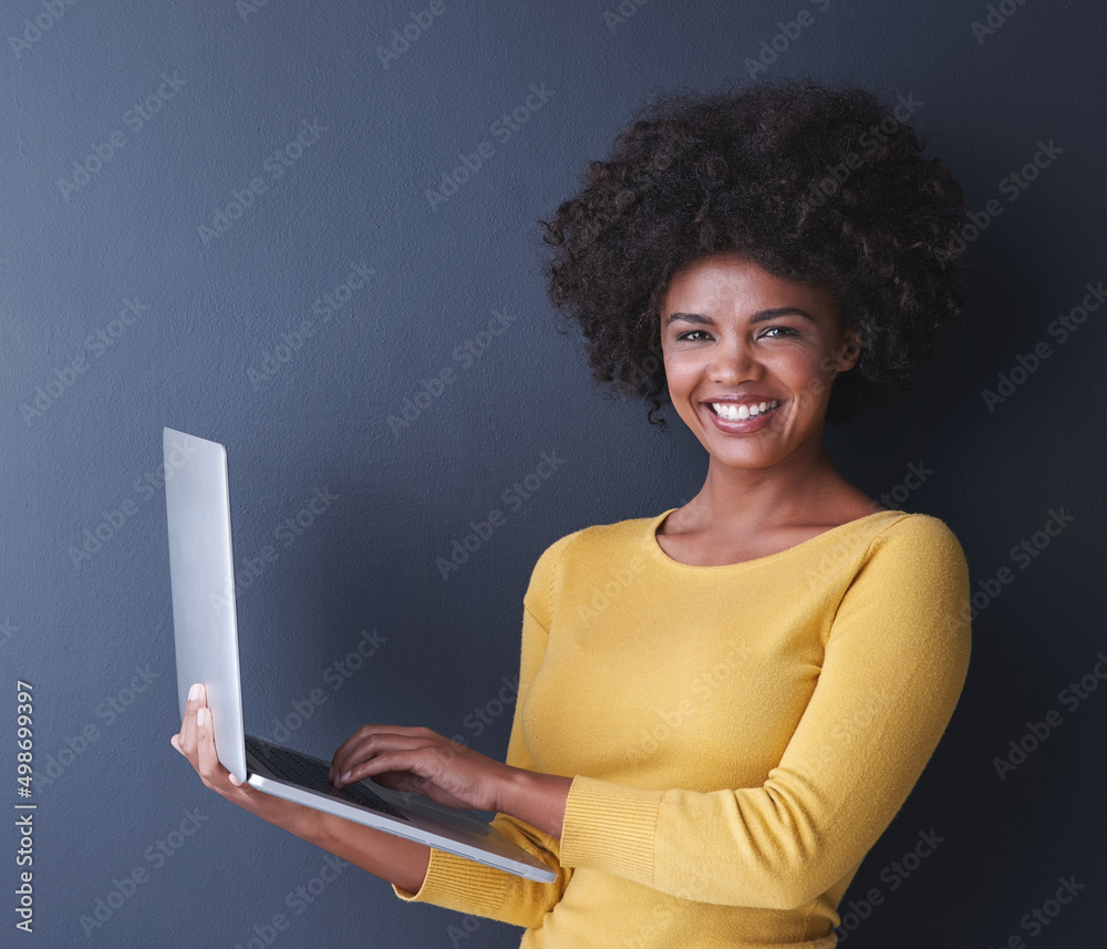 You cant say laptop without a smile on your face. Studio shot of a young woman using her laptop against a grey background. You cant say laptop without a smile on your face. Studio shot of a young woman using her laptop against a grey background.