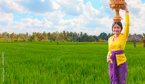 Fotografie Portrait of balinese girl in traditional costume with yellow umbrella walking on