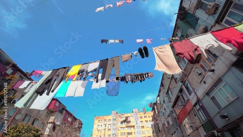 Laundry hung on clotheslines between apartment buildings. Sunny weather, humid climate and blue sky. Old dilapidated houses in a dangerous area. Historical buildings. Favela. Georgia Batumi. photo