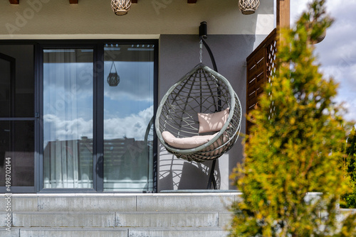 Bilde på lerret Modern hanging rattan chair with gray pillows on the summer garden terrace