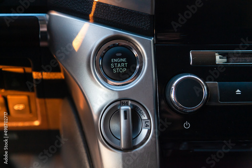 Close-up car engine ignition start and stop button on the dashboard, electric key, modern gray design with chrome elements on the inner panel. Auto service