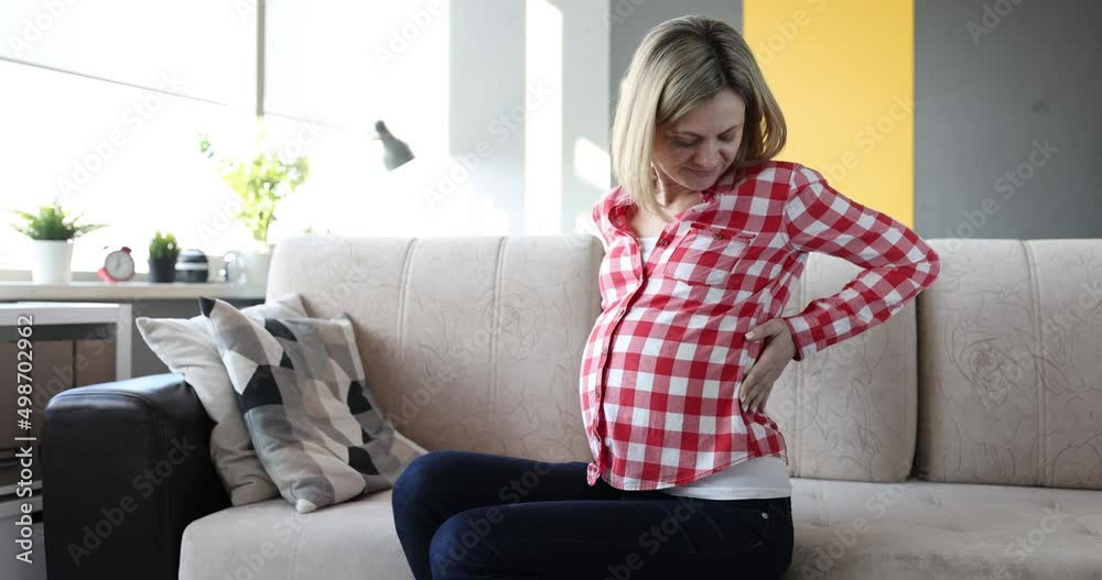 Pregnant woman with severe back pain on couch closeup Pregnant woman with severe back pain on couch closeup