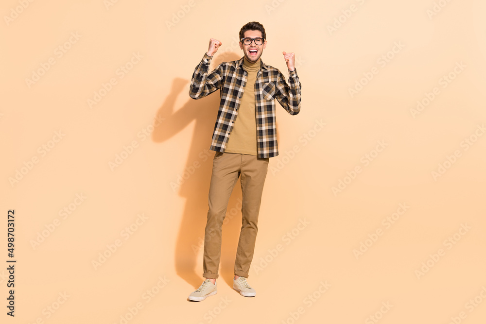 Fototapeta premium Full length body size view of attractive cheerful lucky guy rejoicing having fun isolated over beige pastel color background