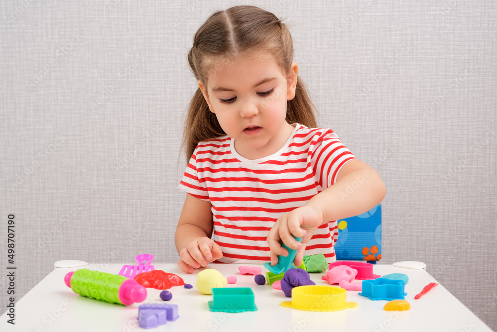 creative classes with plasticine at home, little girl sculpts different figures from multicolored plasticine and molds