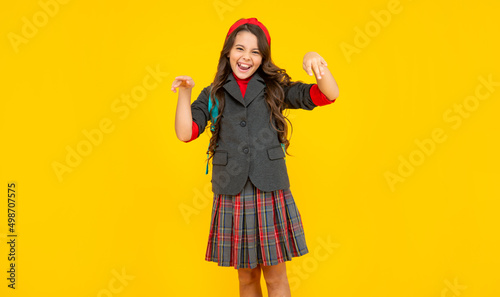 laughing kid in school uniform and backpack on yellow background, education