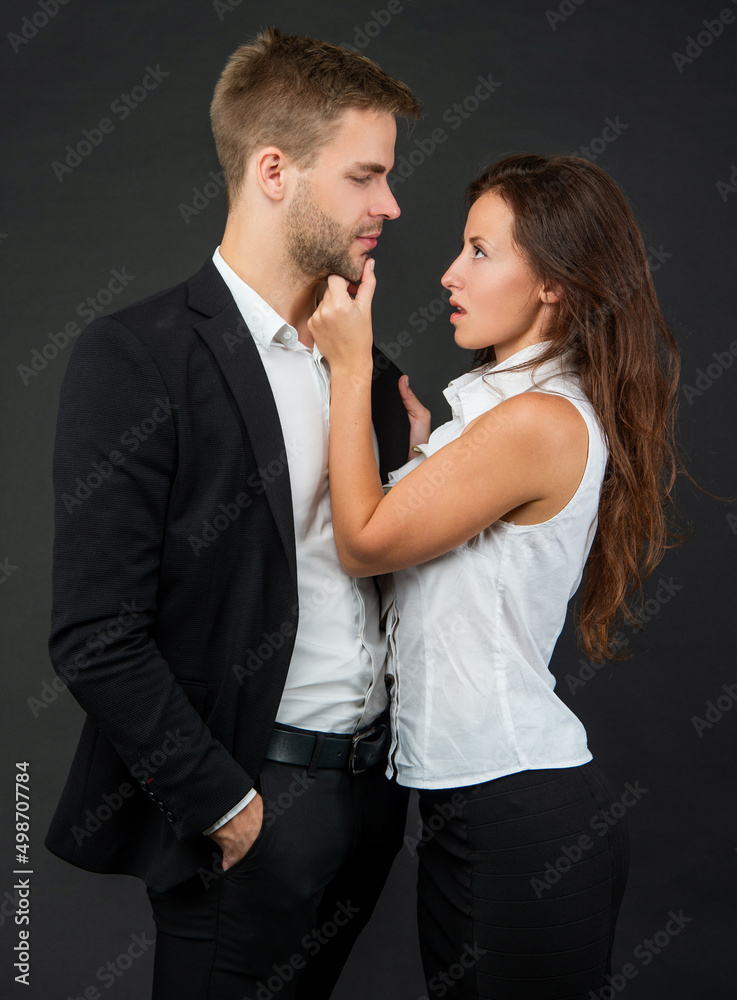 sexy man and woman in business look on black background, couple