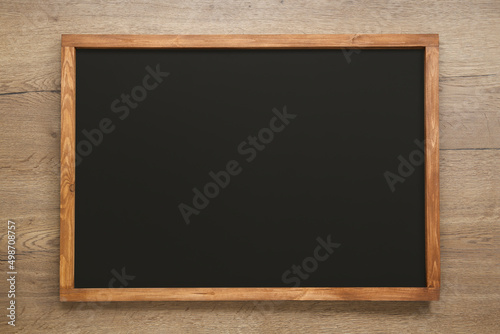 Clean black chalkboard on wooden background, top view
