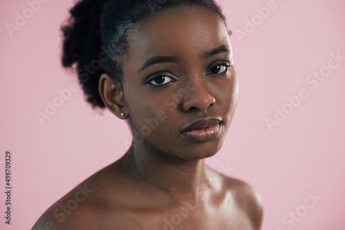 Looking in the camera. Portrait of young african american woman that is against pink background
