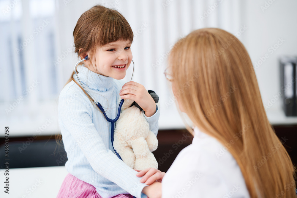 Little girl patient checking heartbeats female doctor in hospital by stethoscope Little girl patient checking heartbeats female doctor in hospital by stethoscope