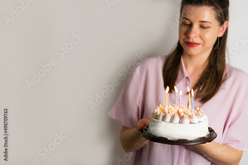 Woman celebrating a birthday with a cake with candles in a shirt in lilac trendy color of the year