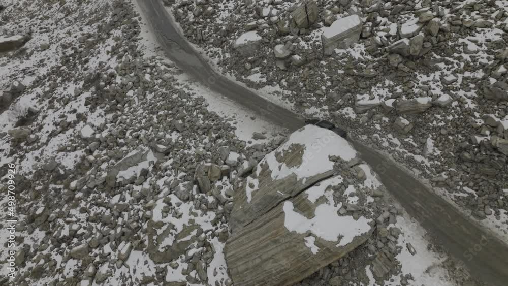 Aerial shot of car in the street with snow caped mountain in the side. Aerial shot of car in the street with snow caped mountain in the side.