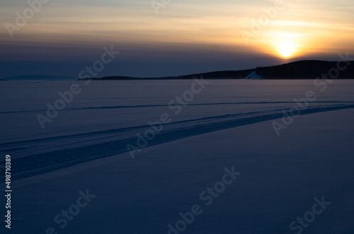 The last rays of the sun at sunset. The sun sets behind the mountains in the snowy desert.