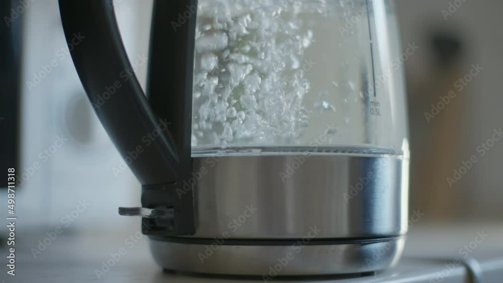 Close-up transparent plastic kettle indoors with water pouring inside. Electric kitchen appliance with liquid filling in Close-up transparent plastic kettle indoors with water pouring inside. Electric kitchen appliance with liquid filling in