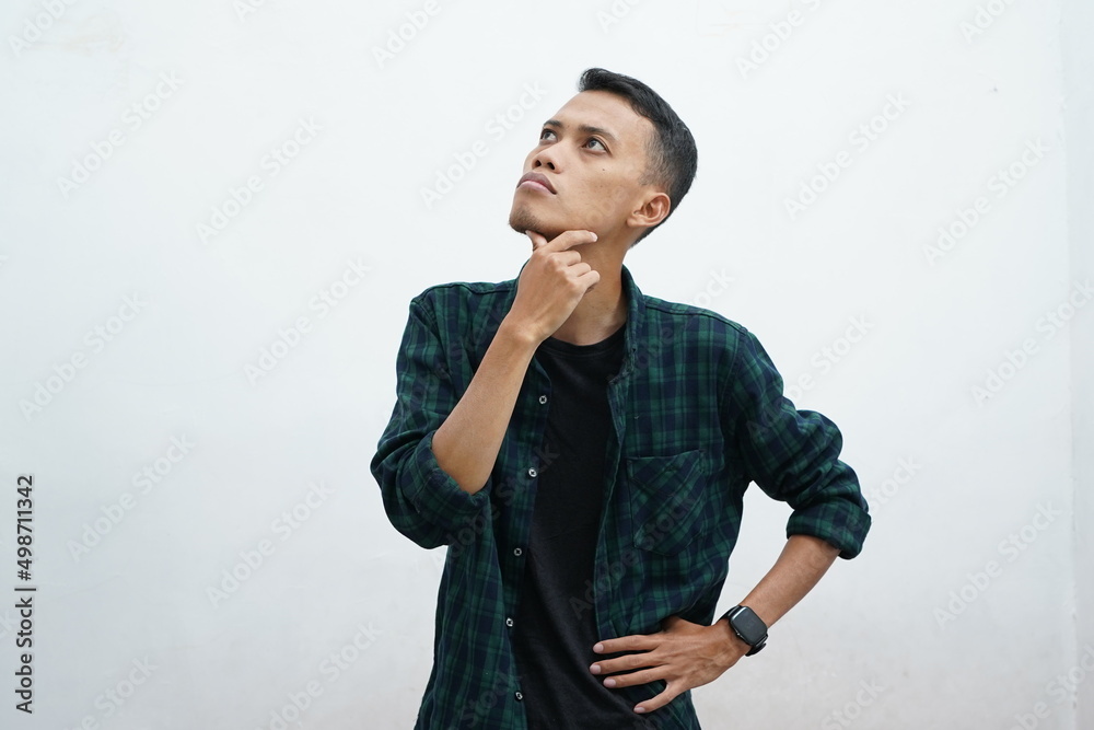 Portrait of a thinking young Asian man wearing casual clothes looking up isolated over white background Portrait of a thinking young Asian man wearing casual clothes looking up isolated over white background
