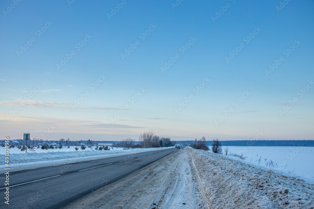 Winter evening landscape, road in the foreground. Sunset sky over the horizon. Winter evening landscape, road in the foreground. Sunset sky over the horizon.