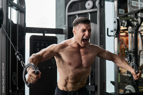 Muscular man working out in gym, strong male torso abs.