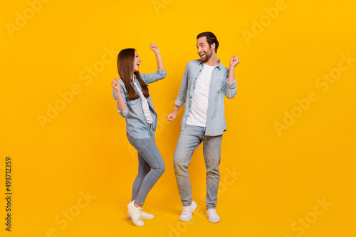 Full length body size view of attractive cheerful funky people dancing having fun isolated over bright yellow color background