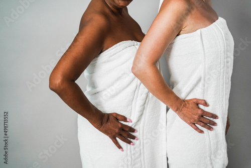 Multiracial senior women with diverse skin and body having fun ogether while wearing body towels - Focus on hands photo