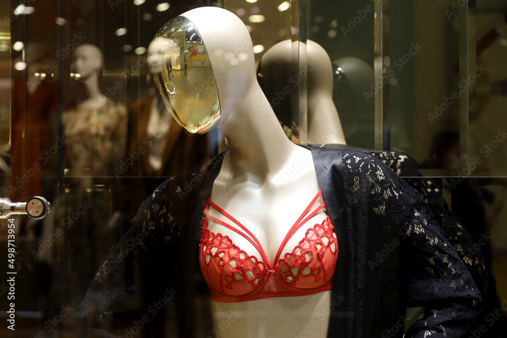 Female mannequin in red lace bra and black nightdress. Lingerie store, view  throw the glass Stock Photo
