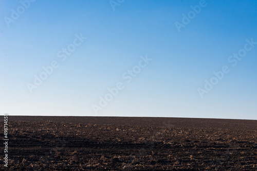 Ploughed field and blue sky as background.